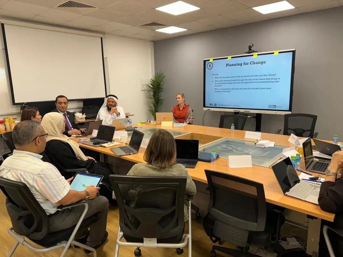 Benegas leading a Planning for Change training session with Bahrain Teachers College administration seated around a conference table