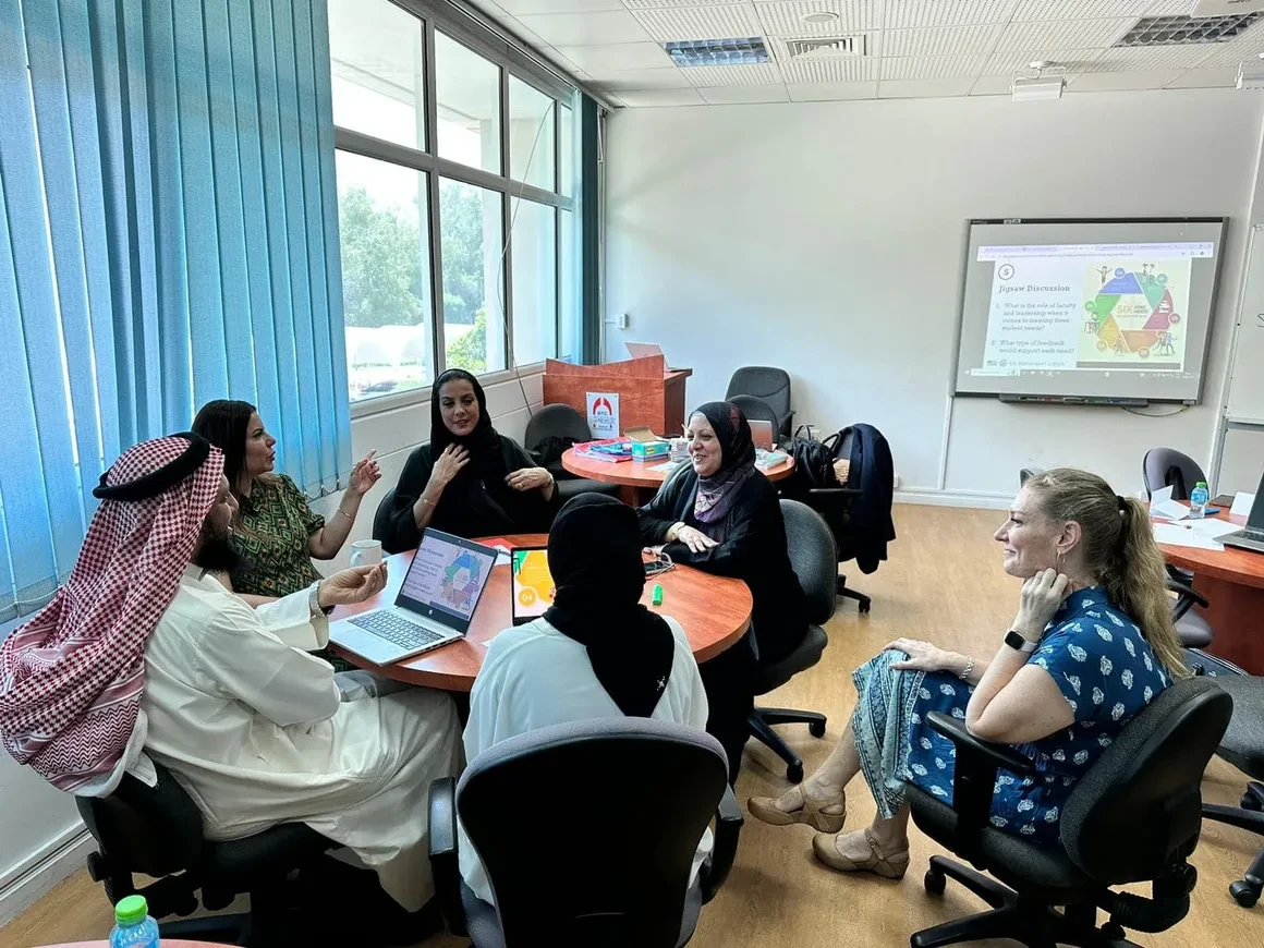 Benegas facilitating a Jigsaw Discussion training session with Bahrain Teachers College faculty seated around a round table