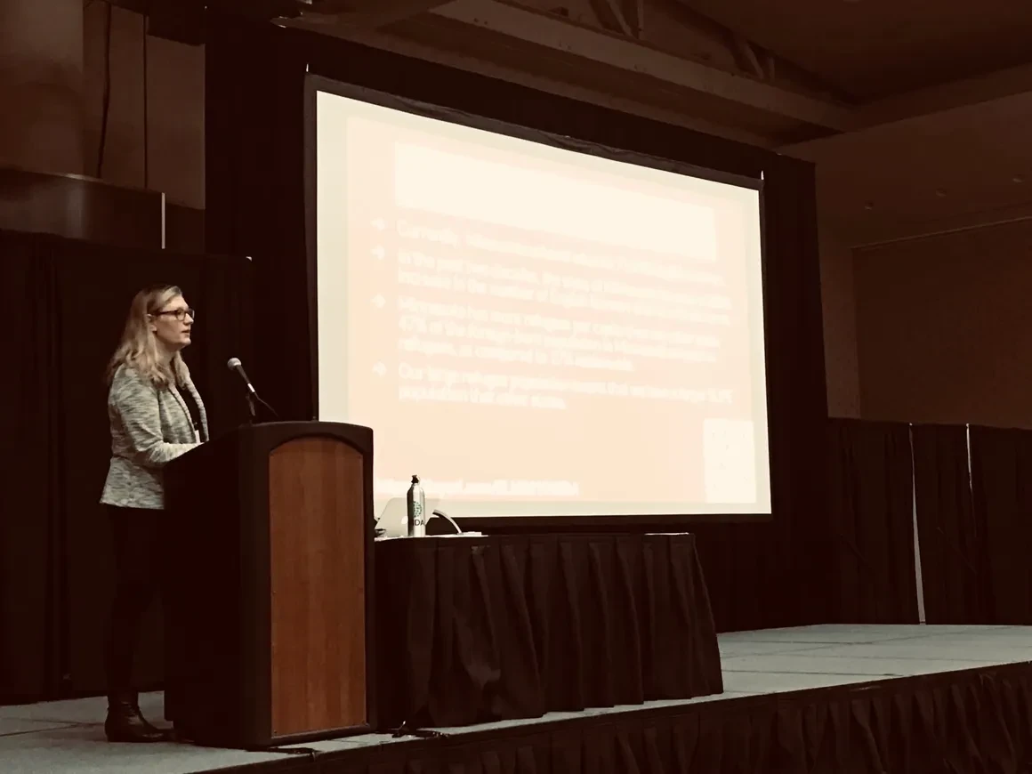 Woman speaking at podium with projection screen at professional development event
