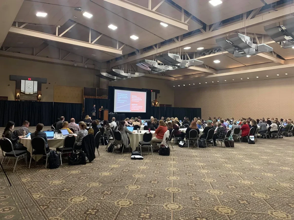 Large conference ballroom filled with attendees seated at round tables for a WIDA Conference workshop on ELD teacher leadership